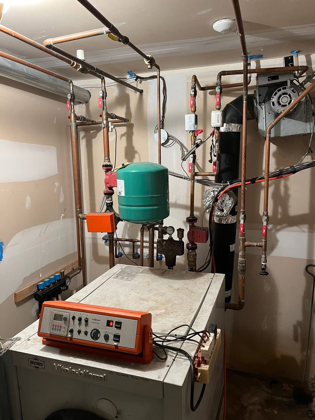 Old floor-standing oil-fired boiler with aging copper piping and a green expansion tank