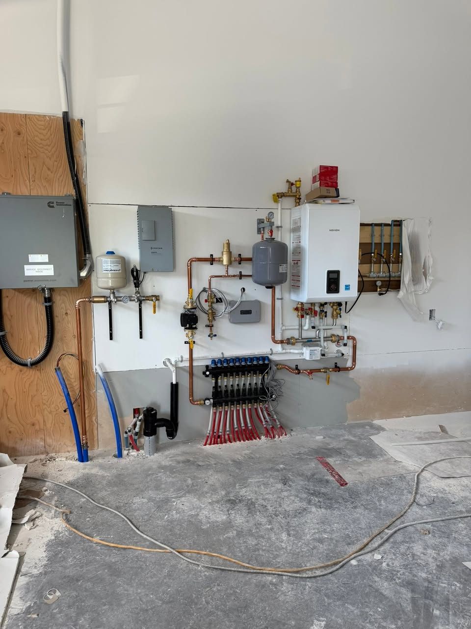 Navien wall-hung boiler and in-floor radiant manifold with PEX loops in a new-build mechanical room