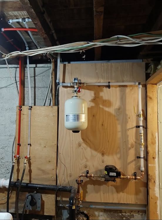 Replacement water service on a plywood backer board with a new expansion tank, meter and neatly strapped copper and PEX